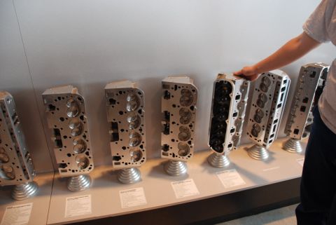 1996 Ford Bronco - Engine cylinder heads are displayed on stands in a museum or exhibit setting.