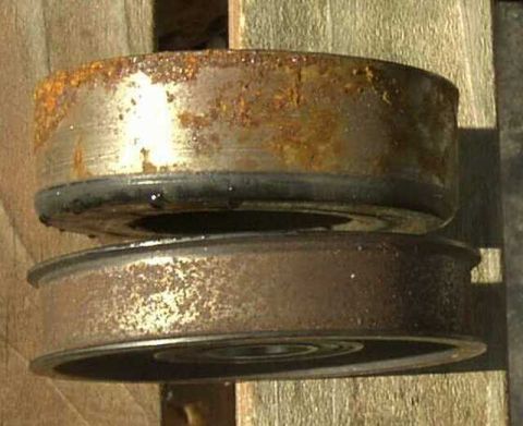 1997 Ford Taurus - These two heavily rusted idler pulleys are shown up close, resting on a wooden surface.