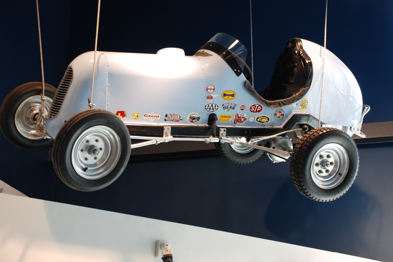 Light blue vintage race car suspended, covered in various sponsor stickers
