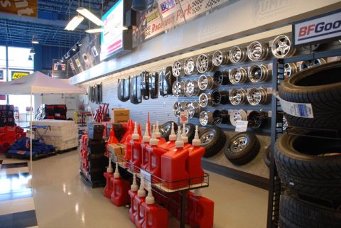 1996 Ford Bronco - A view inside a Summit Racing store displays a variety of automotive parts, including wheels, tires, and red fuel containers on shelves.
