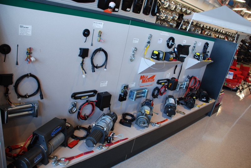 Display wall with various winches, cables, and tow hooks, Mile Marker branding
