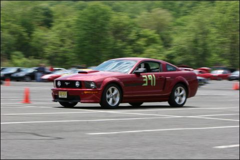 2001 Mercury Grand Marquis - A red Ford Mustang competes in an autocross event, with other vehicles visible in the background.