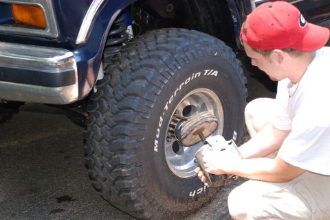 1996 Ford Bronco - A man polishes the large tire of a blue 1996 Ford Bronco.