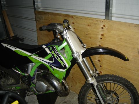 1988 Ford Bronco - A green and black Kawasaki dirt bike is parked indoors, showing its front section and handlebars.