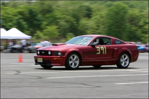 2001 Mercury Grand Marquis - A red Ford Mustang with racing number 391 on its door navigates a course during an event.