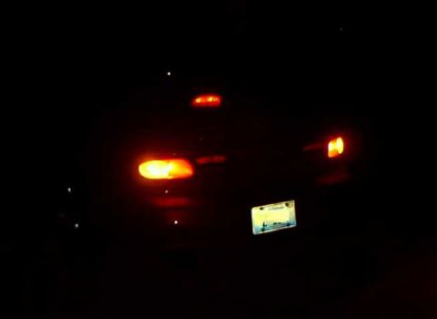1997 Ford Taurus - Night shot of the rear of a car in near-total darkness, showing glowing amber and red tail lamps, a center high-mount stop lamp and an illu…