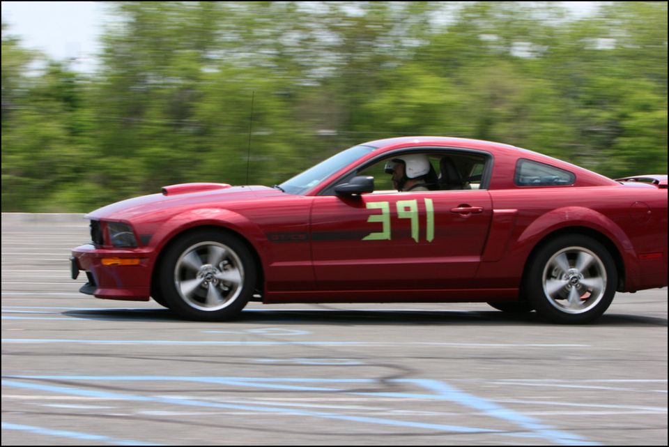 Red Ford Mustang with green number 391 on the door, driving on a track