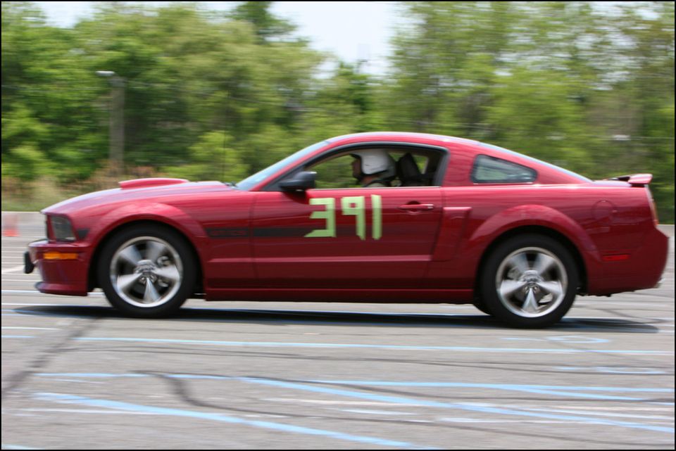Red coupe with green racing numbers 391 on the side, seen from the side at an autocross event