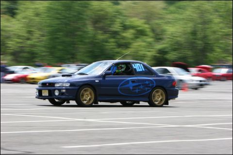 2001 Mercury Grand Marquis - A blue Subaru Impreza WRX STI with racing decals and number 401 competes on a track with other cars blurred in the background.