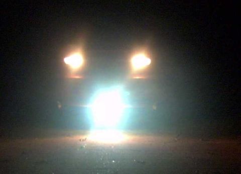 1997 Ford Taurus - Headlights of a car shine brightly in the dark, illuminating the road ahead.