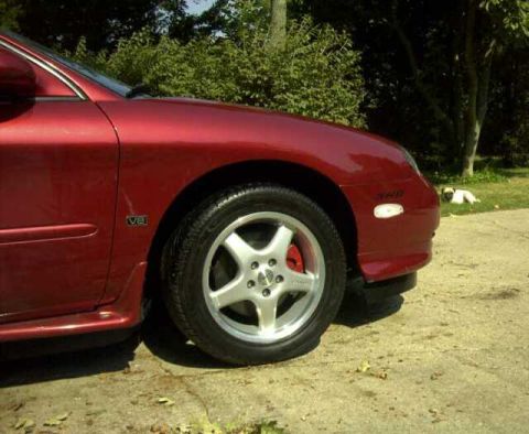 1997 Ford Taurus - Close-up of a red sedan's front passenger side, showing the wheel and fender detail.