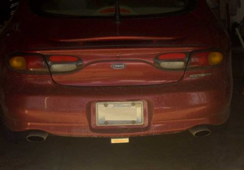 1997 Ford Taurus - The rear of a red sedan is shown, its taillights, exhaust pipes, and a license plate.