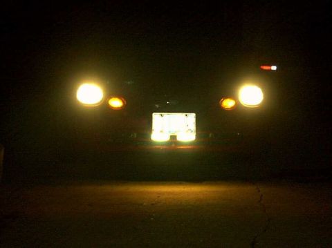 1997 Ford Taurus - The rear of a car is visible at night, with its license plate and taillights illuminated.