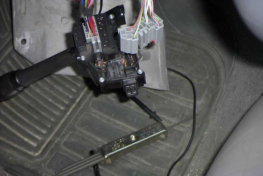 Close-up of a car's wiper switch wiring harness and connectors on the floor mat