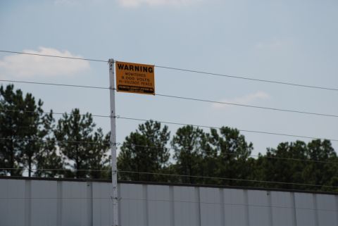 1996 Ford Bronco - Warning sign indicates a monitored high-voltage fence with 9,000 volts.