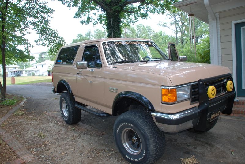 Tan Ford Bronco with aftermarket bull bar and yellow fog lights