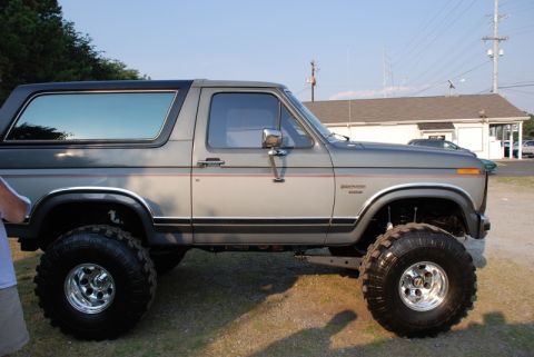 1996 Ford Bronco - This lifted Ford Bronco features a two-tone paint scheme and prominent off-road tires.