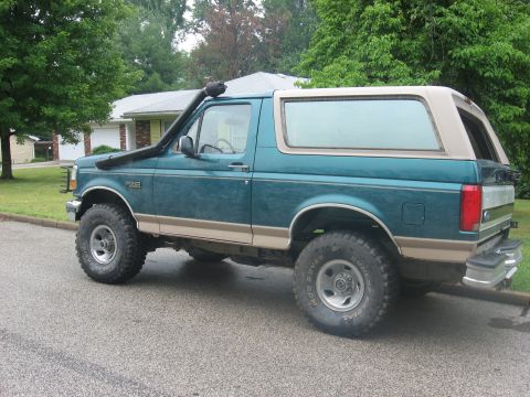 1996 Ford Bronco - Side view of a teal and tan 1996 Ford Bronco equipped with a snorkel and off-road tires.