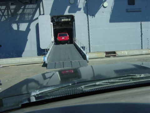 1994 Ford Bronco - A red SUV is being driven onto a large vessel via a ramp.