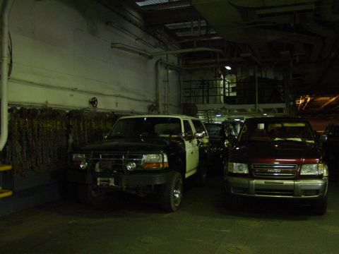 1994 Ford Bronco - A 1994 Ford Bronco and an Isuzu Trooper are parked side-by-side within a dimly lit cargo hold.