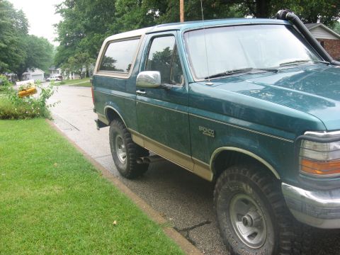 1996 Ford Bronco - This 1996 Ford Bronco features a snorkel and tan two-tone trim, seen from a three-quarter front view on a suburban street.