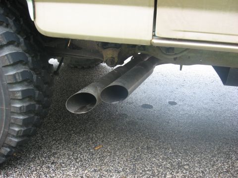 1996 Ford Bronco - Close-up view of dual exhaust pipes and a tire on the underside of a vehicle.