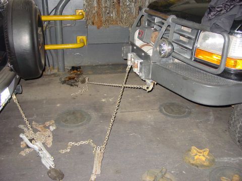 1994 Ford Bronco - A Ford Bronco is secured with chains inside a transport vehicle, with its spare tire mounted on the side.