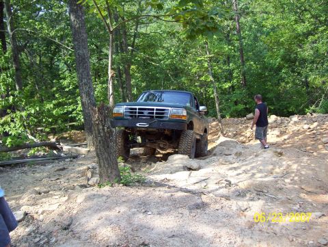 1978 Ford Bronco - A green Ford F-150 navigates a challenging off-road course with a man watching.