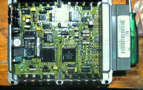 1997 Ford Taurus - An opened engine control module with its cover removed, showing the green circuit board with large surface-mount processor chips and a smal…
