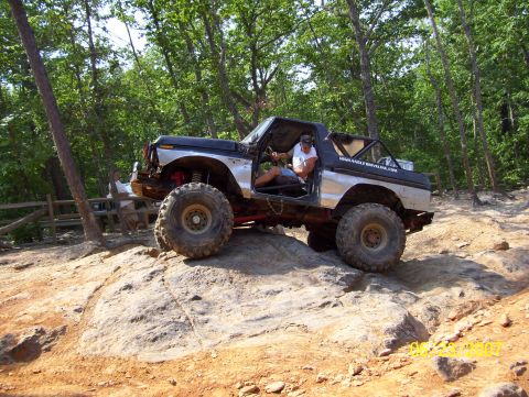 1978 Ford Bronco - A modified off-road vehicle navigates a challenging rocky terrain on a sunny day.