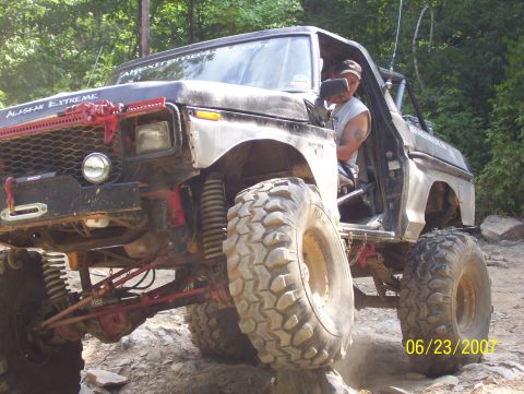 1978 Ford Bronco - A heavily modified 1978 Ford Bronco navigates a rocky trail with a driver visible.