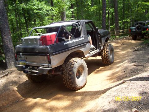 1978 Ford Bronco - A modified 1978 Ford Bronco navigates a wooded dirt path, with another off-road vehicle visible in the background.