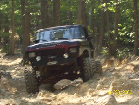 1978 Ford Bronco - 1978 Ford Bronco navigating a challenging off-road course with rocky obstacles.