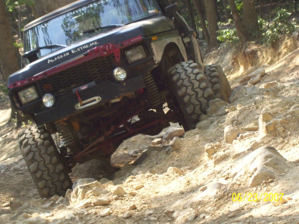 Off-road vehicle with "Alaskan Extreme" on windshield climbing rocky trail
