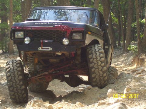 1978 Ford Bronco - A modified 1978 Ford Bronco navigates a challenging rocky terrain on a sunny day.