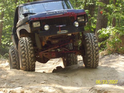 1978 Ford Bronco - Modified 1978 Ford Bronco tackling an off-road trail with large tires and suspension.