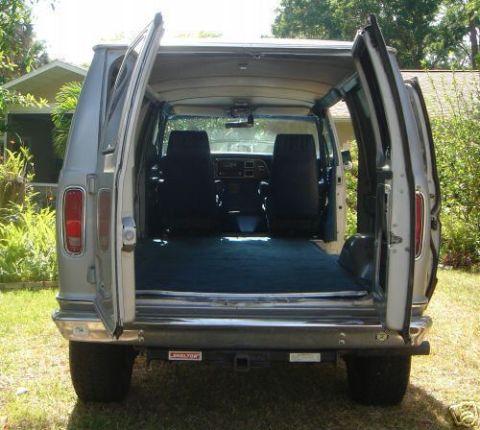 1978 Ford E250 - Rear view of a silver 1978 Ford E250 van with its rear doors open, revealing the interior and seating.