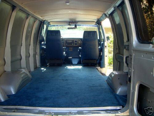 Empty van cargo interior looking forward, blue carpet, grey panels and two blue bucket seats