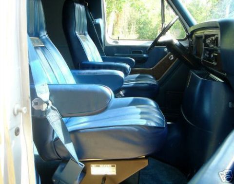 1978 Ford E250 - The interior of a 1978 Ford E250 van shows two rows of blue captain's chairs and a dashboard.