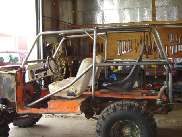 Modified off-road vehicle interior with roll cage, racing seat, and dashboard. Orange body panels visible