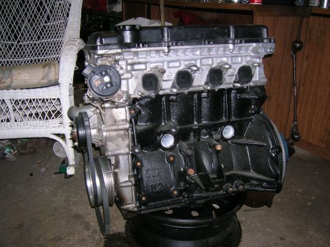 1992 Nissan 240SX - Engine block with distributor and belts, mounted on a stand. Text '53F W2' visible on block.