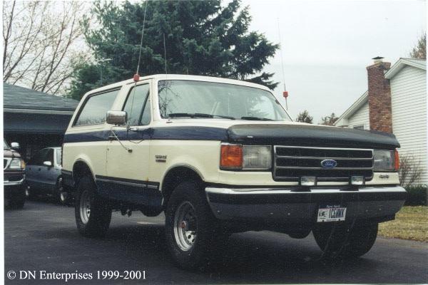 Cream and blue Ford Bronco SUV with hood bra parked in a driveway