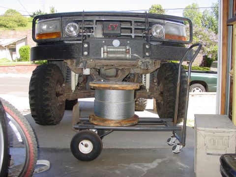 1994 Ford Bronco - Front view of a 1994 Ford Bronco, modified with a winch and a large spool of wire, parked in a garage.