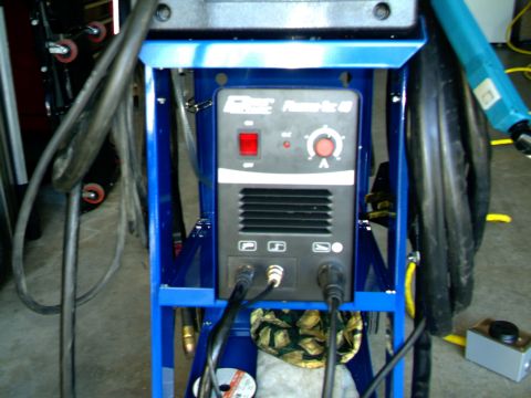 1989 Ford Bronco - A welding machine is mounted on a blue frame, with various cables connected to it.