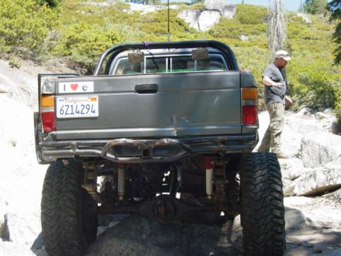 1986 Ford Bronco - This heavily modified pickup truck is navigating a challenging, rocky off-road path.