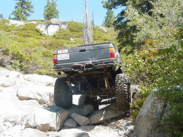 Dark green SUV navigating rocky terrain from the rear