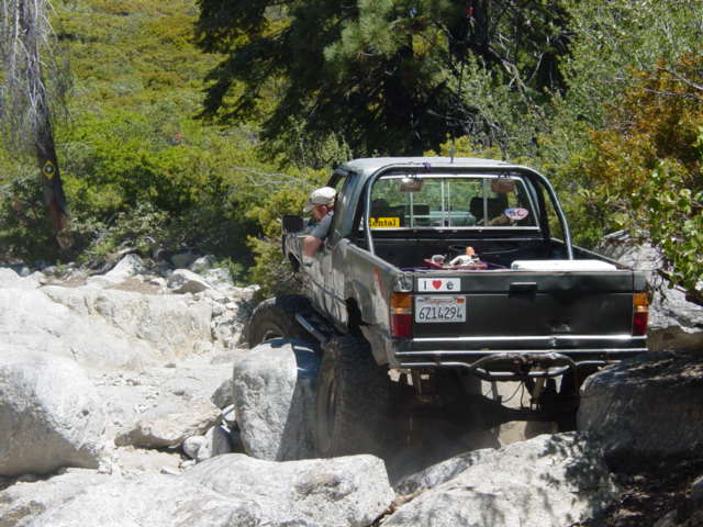 pickup truck driving over rocks on a trail
