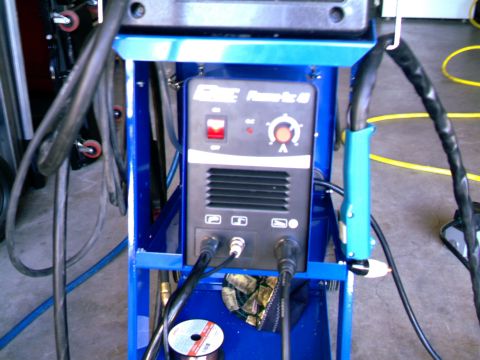 1989 Ford Bronco - A welding machine is mounted on a blue cart, a power switch, adjustment dial, and various cables.