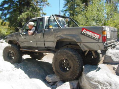 1986 Ford Bronco - This modified pickup truck navigates a rocky trail with its large tires.