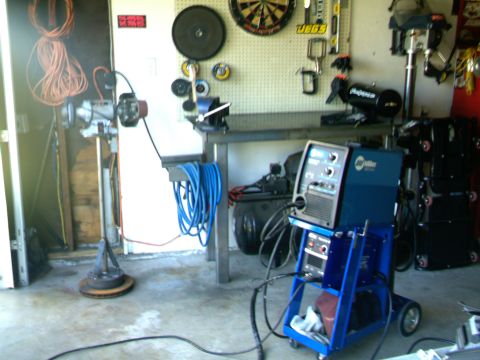 1989 Ford Bronco - A garage workshop is equipped with a Miller welding machine, air compressor, and a variety of tools mounted on the wall.